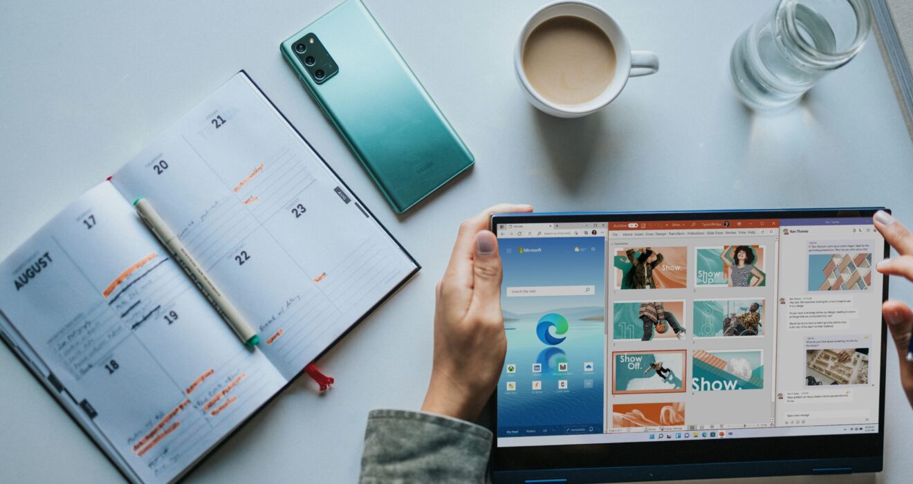 person using Windows 11 computer beside white ceramic mug on white table
