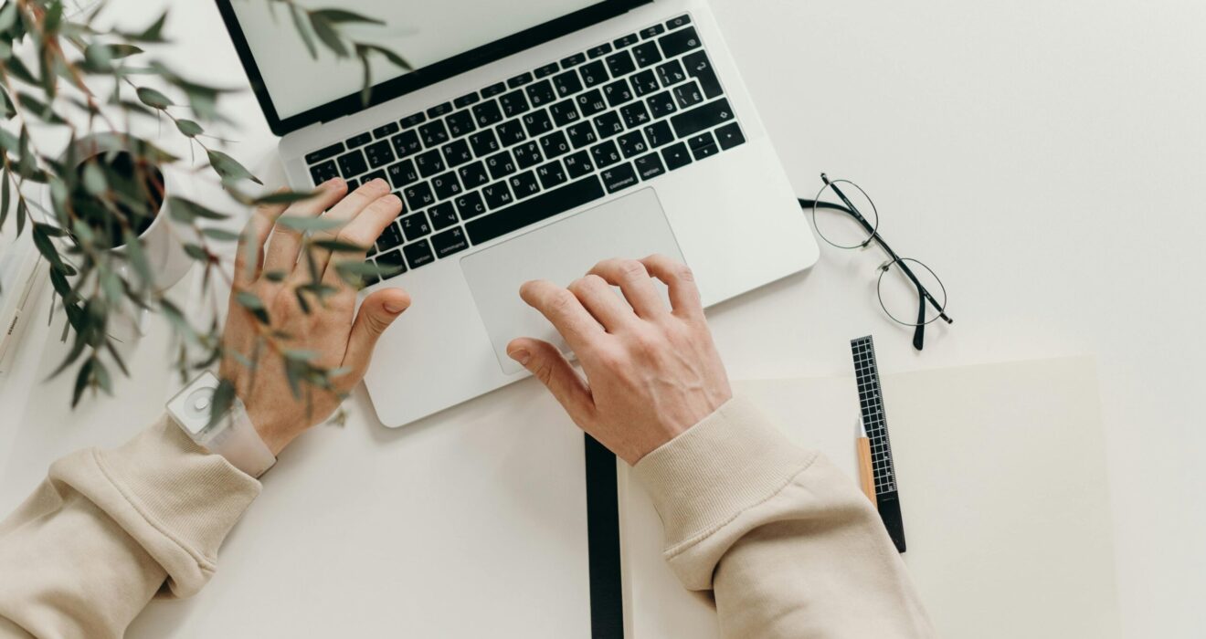 Free An overhead view of a person working on a laptop in a minimalist home office setting. Stock Photo