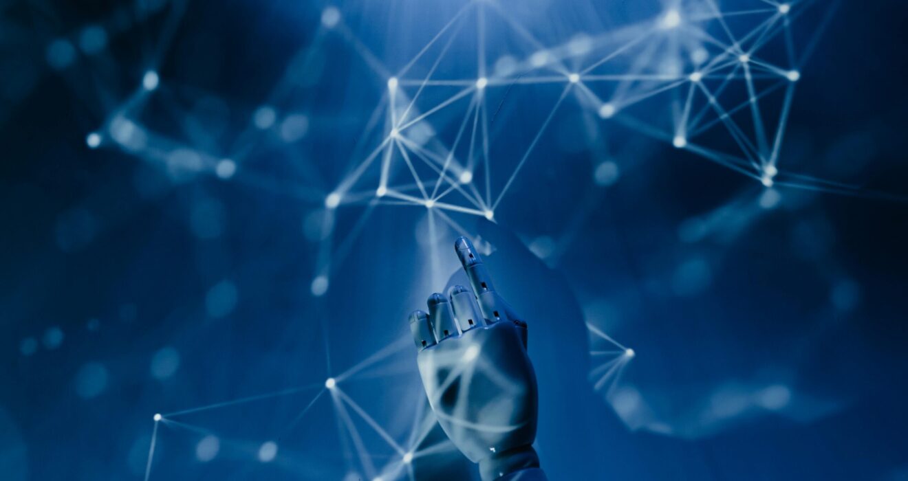 Free A robotic hand reaching into a digital network on a blue background, symbolizing AI technology. Stock Photo